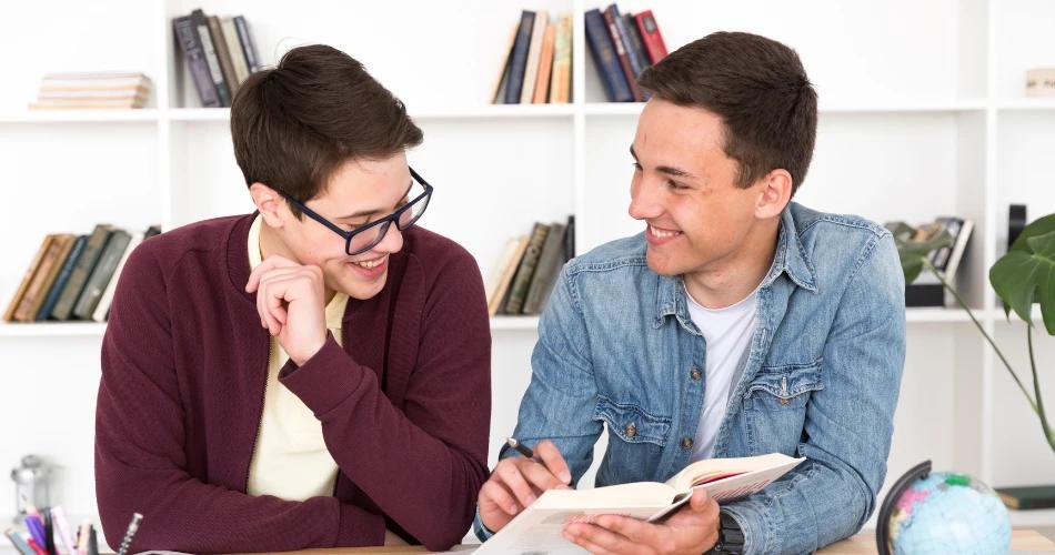 Two students discussing NEET admission quotas with a book and globe in study room background