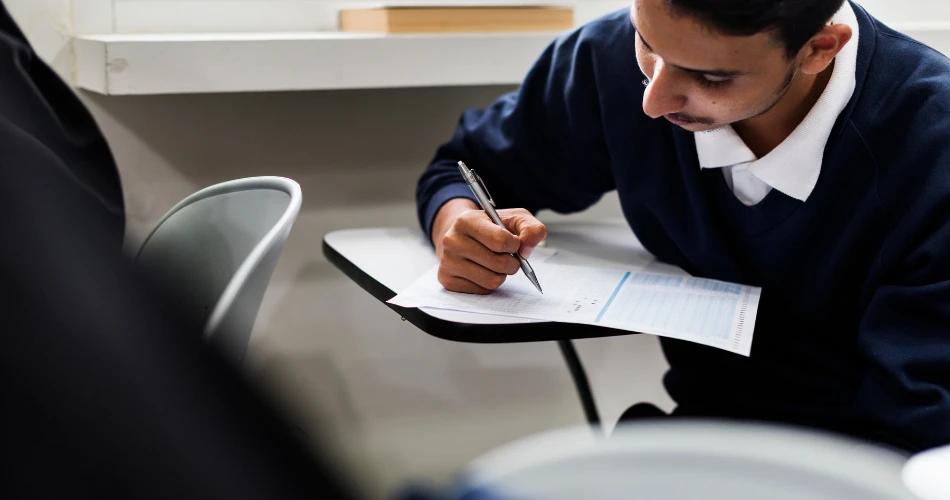 A student focused on filling out an exam sheet, reflecting the release of Maharashtra HSC and SSC supplementary exam hall tickets.