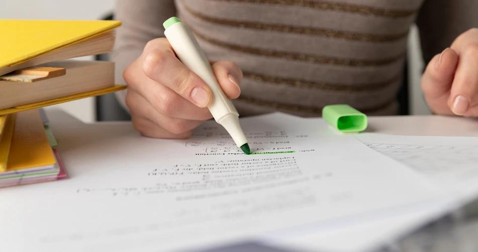 A student reviewing and highlighting key information on a study sheet in preparation for the Additional MAH CET exam.