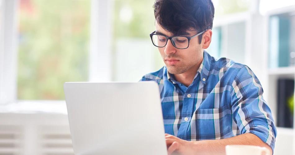 Student checking CUET (UG) 2025 exam city intimation slip on laptop in a study room.